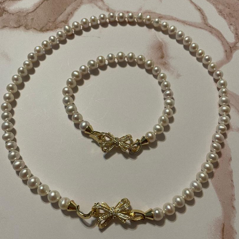 Pearl necklace with gold clasp on a marble surface