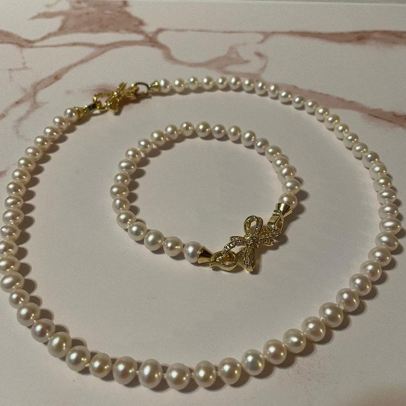 Pearl necklace and bracelet set on a marble surface